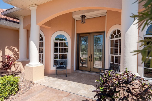 entrance to property with stucco siding, french doors, and a tile roof