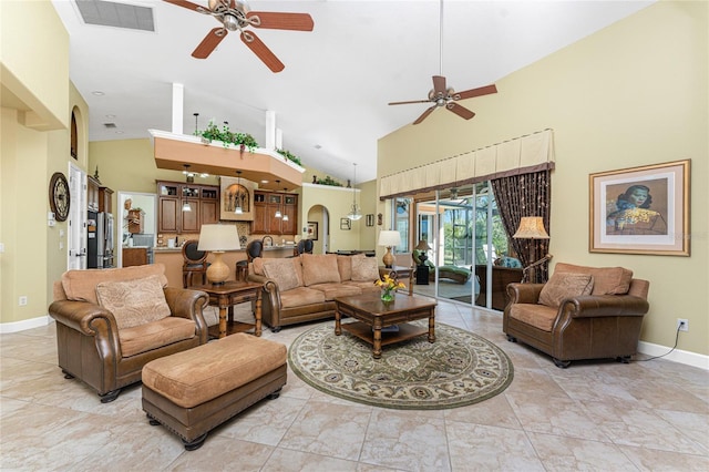 living area featuring baseboards, visible vents, high vaulted ceiling, arched walkways, and ceiling fan