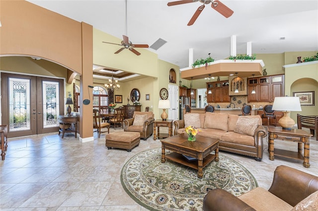 living room with baseboards, high vaulted ceiling, arched walkways, french doors, and ceiling fan with notable chandelier