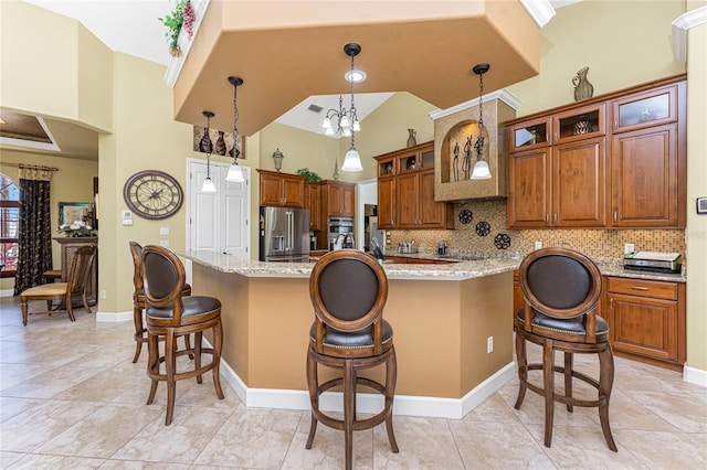 kitchen with a kitchen bar, stainless steel appliances, brown cabinetry, decorative backsplash, and a large island with sink