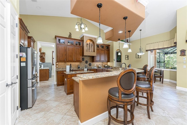 kitchen featuring a kitchen bar, an island with sink, tasteful backsplash, brown cabinetry, and stainless steel fridge with ice dispenser