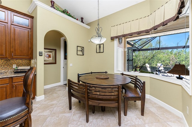 dining space with arched walkways and baseboards