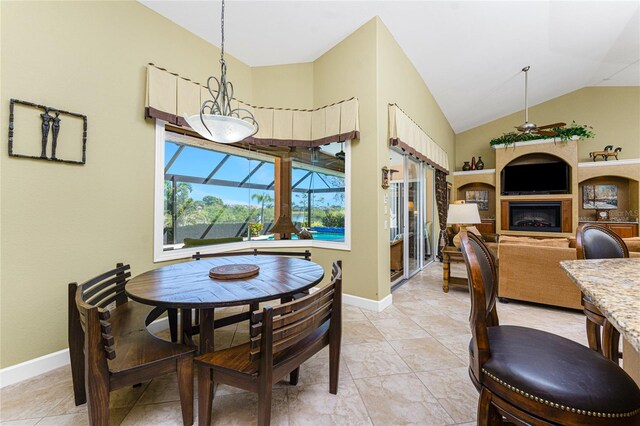 dining area with lofted ceiling, a glass covered fireplace, a sunroom, light tile patterned floors, and baseboards