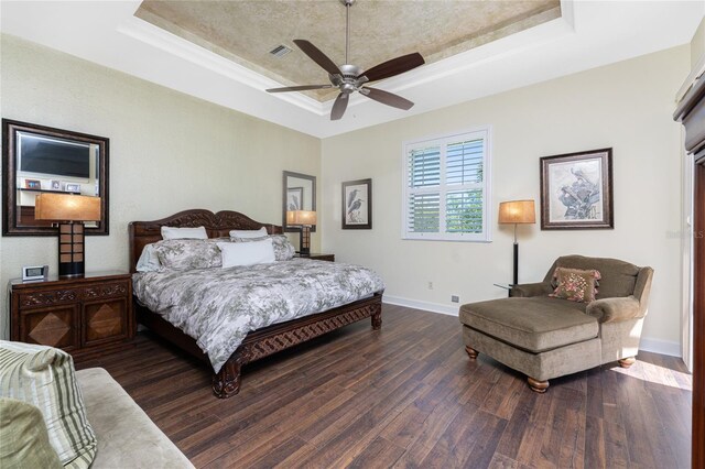 bedroom with a tray ceiling, wood finished floors, baseboards, and ceiling fan