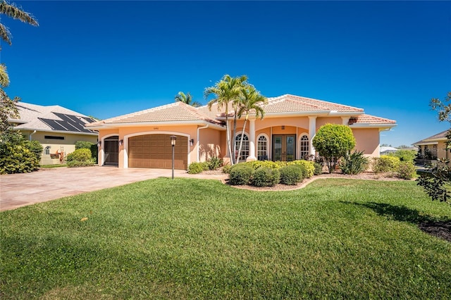 mediterranean / spanish house with french doors, a garage, driveway, and a tile roof