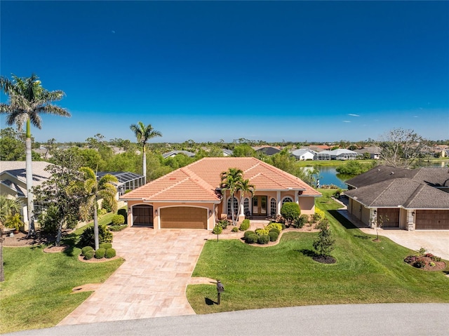 mediterranean / spanish home with an attached garage, stucco siding, a front lawn, a tiled roof, and decorative driveway