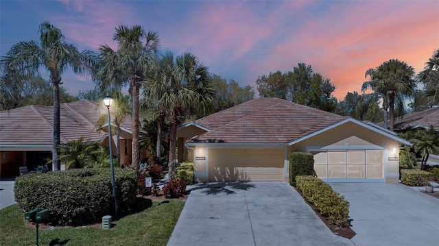 view of front of house featuring stucco siding, a tiled roof, concrete driveway, and a garage