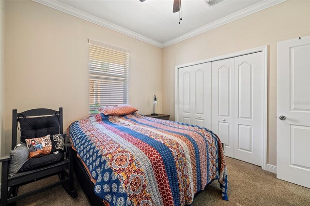 carpeted bedroom featuring a closet, visible vents, ornamental molding, and a ceiling fan