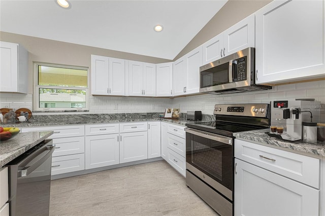 kitchen with vaulted ceiling, decorative backsplash, appliances with stainless steel finishes, white cabinets, and stone countertops