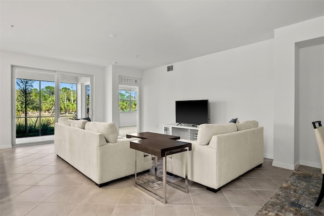 living area with light tile patterned floors, visible vents, and baseboards