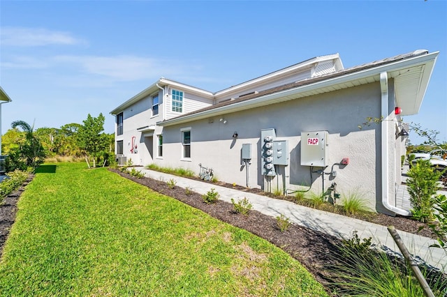 exterior space with stucco siding and a lawn