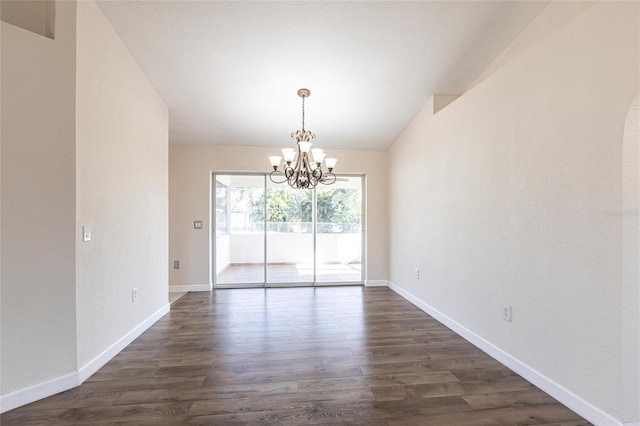 spare room featuring a chandelier, vaulted ceiling, baseboards, and dark wood-style flooring