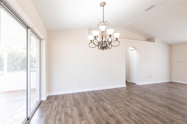 empty room featuring visible vents, wood finished floors, arched walkways, baseboards, and vaulted ceiling