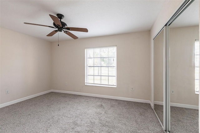 unfurnished bedroom with baseboards, a closet, carpet floors, and ceiling fan