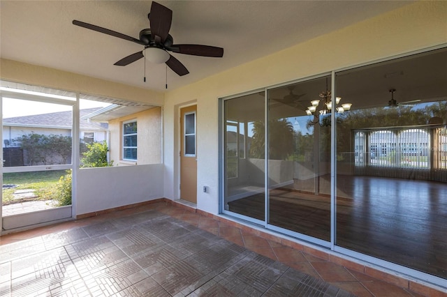 unfurnished sunroom with ceiling fan with notable chandelier