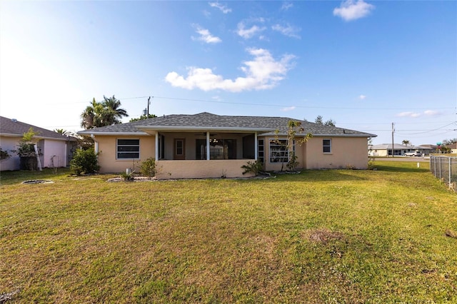 back of property with a yard, fence, and stucco siding