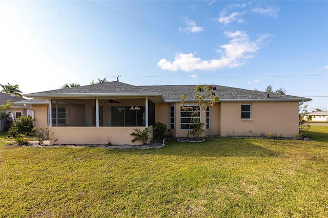 back of property featuring a lawn, a sunroom, roof with shingles, and stucco siding