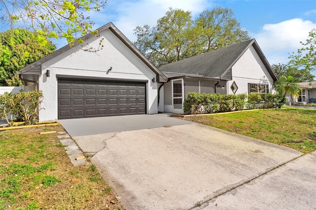 view of front of home with stucco siding, a front yard, an attached garage, and driveway