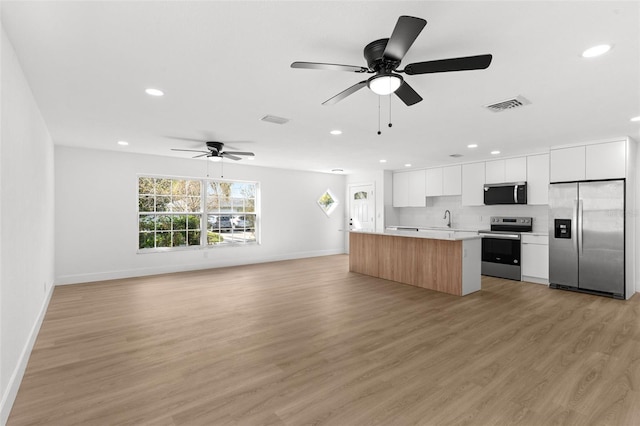 kitchen with visible vents, modern cabinets, a sink, a center island, and stainless steel appliances