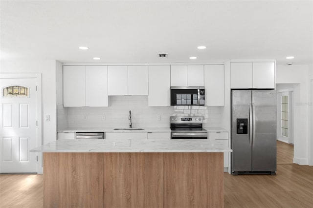 kitchen featuring light wood finished floors, appliances with stainless steel finishes, white cabinetry, and a sink