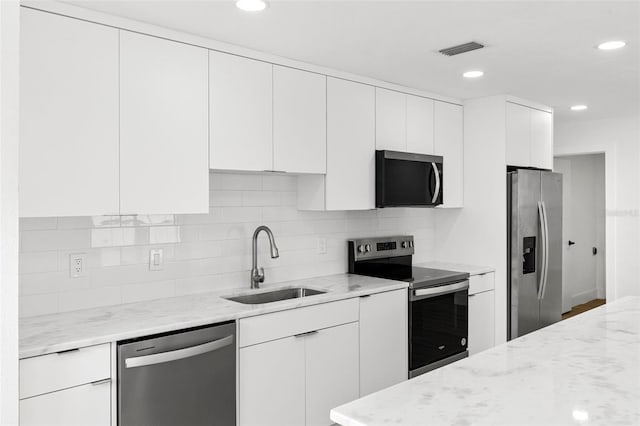 kitchen featuring decorative backsplash, visible vents, appliances with stainless steel finishes, and a sink