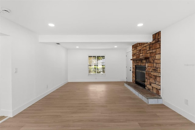 unfurnished living room with recessed lighting, baseboards, a fireplace, and light wood finished floors