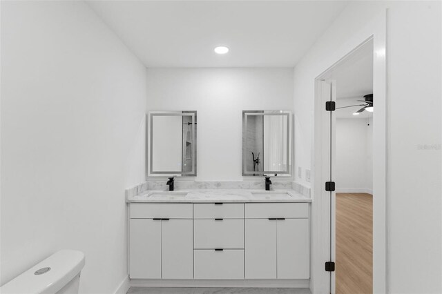 full bath featuring double vanity, toilet, baseboards, and a sink