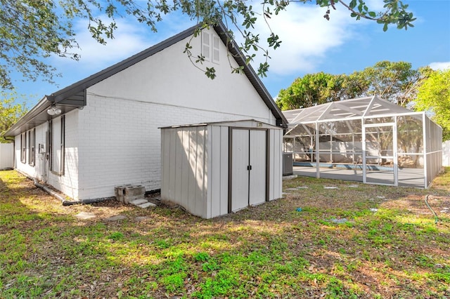 view of side of property featuring brick siding, a swimming pool, glass enclosure, an outbuilding, and a storage unit