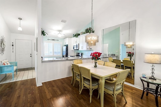 dining space with visible vents, ceiling fan with notable chandelier, and dark wood-style flooring