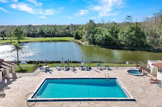 pool with a patio area, fence, and a water view