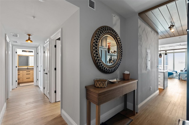 hallway with visible vents, light wood-type flooring, and baseboards