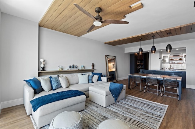 living area featuring baseboards, wood finished floors, and a ceiling fan