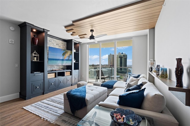 living area featuring baseboards, a wall of windows, a ceiling fan, and wood finished floors