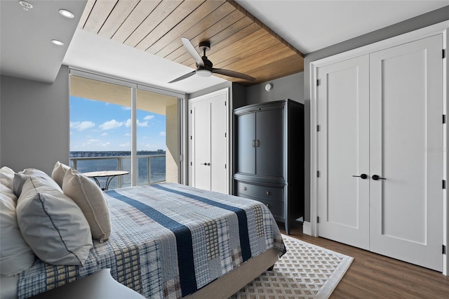 bedroom with dark wood-type flooring, access to outside, expansive windows, recessed lighting, and wooden ceiling