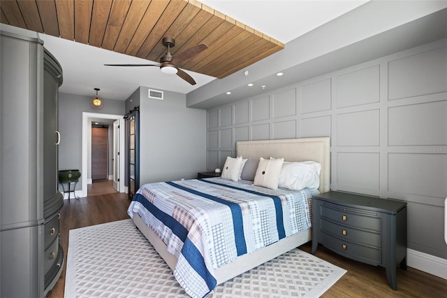 bedroom featuring dark wood-style floors, a decorative wall, and wood ceiling