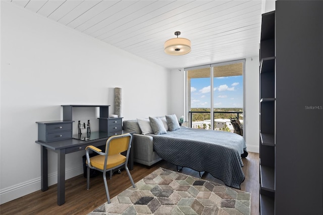 bedroom featuring a wall of windows, wood finished floors, and baseboards