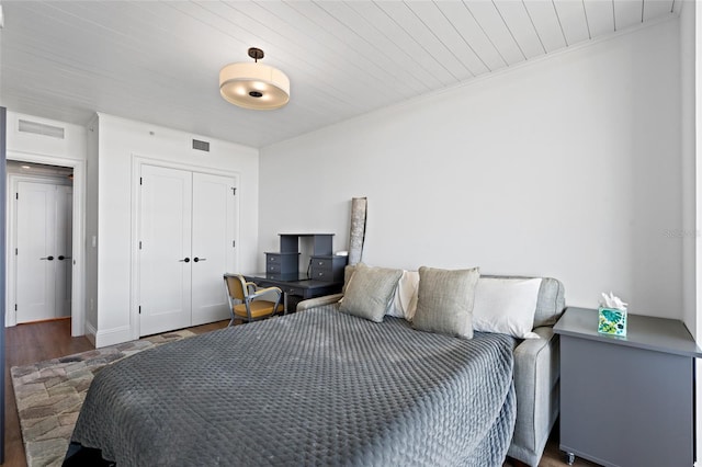 bedroom featuring a closet, visible vents, crown molding, and wood finished floors