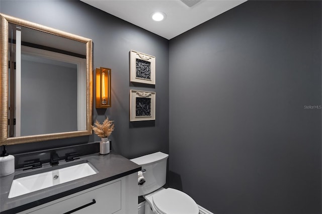 half bath with recessed lighting, toilet, and vanity