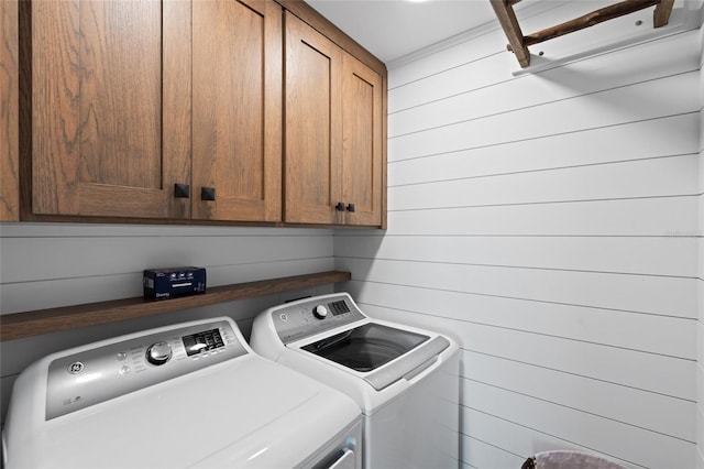 laundry room with washer and dryer, cabinet space, and wood walls