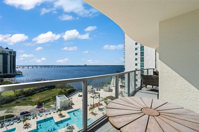 balcony with a city view, central AC unit, and a water view