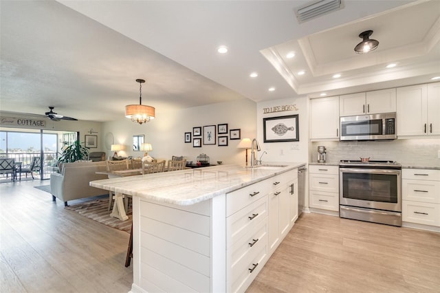 kitchen featuring visible vents, light wood-style flooring, a peninsula, and stainless steel appliances