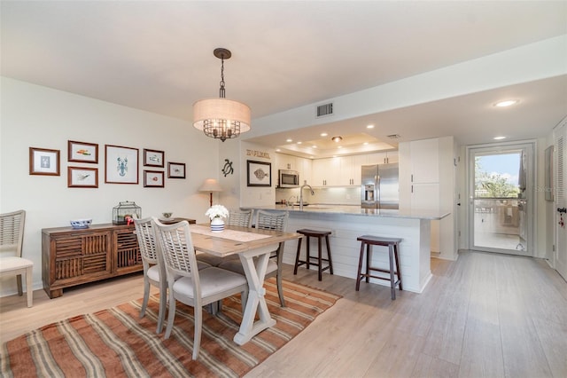 dining area featuring recessed lighting, visible vents, light wood-style flooring, and an inviting chandelier