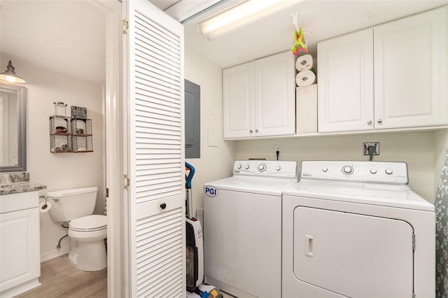 laundry room featuring light wood-style flooring, electric panel, baseboards, and washing machine and clothes dryer