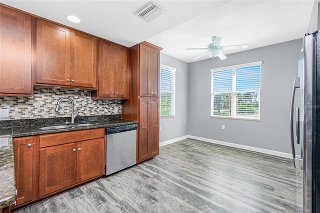 kitchen with visible vents, light wood-style flooring, a sink, dishwasher, and backsplash