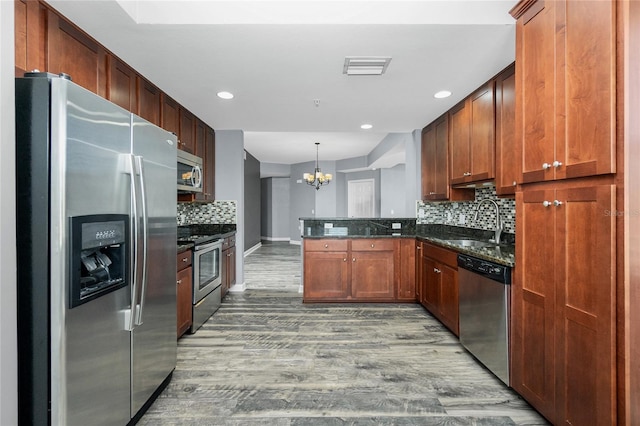 kitchen with wood finished floors, visible vents, a peninsula, a sink, and appliances with stainless steel finishes