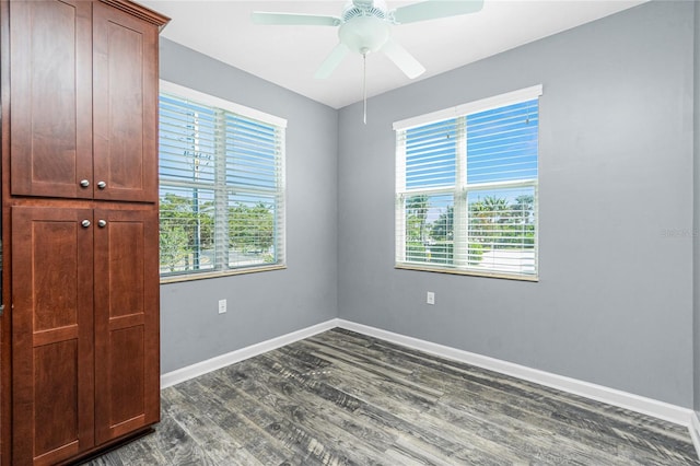 empty room with dark wood-style floors, ceiling fan, and baseboards