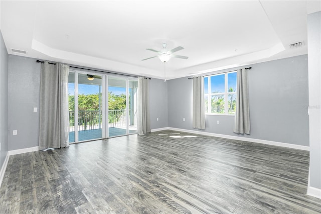 spare room featuring a raised ceiling, wood finished floors, and baseboards