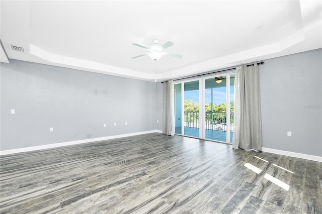 spare room with a ceiling fan, a raised ceiling, baseboards, and wood finished floors