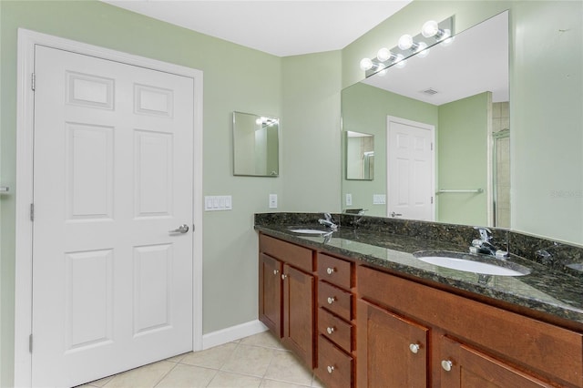 bathroom featuring tile patterned floors, double vanity, baseboards, and a sink