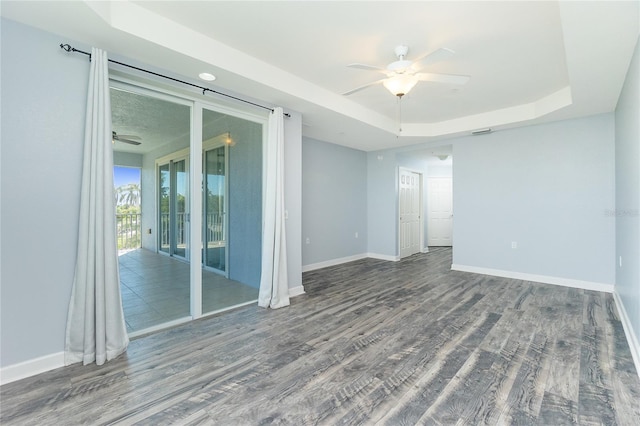 spare room featuring baseboards, a raised ceiling, wood finished floors, and a ceiling fan